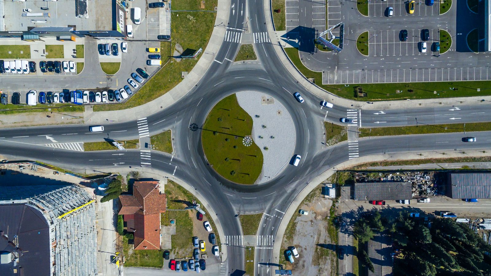 A roundabout seen from above, with cars entering and leaving between apartment blocks