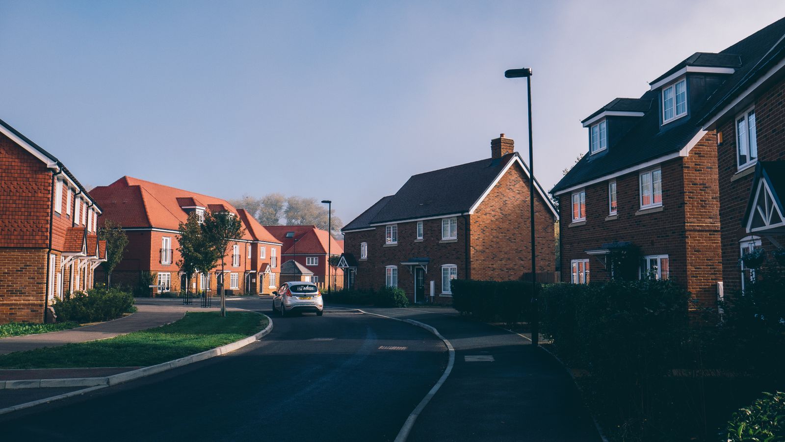 A quiet residential street with brick houses and a lamp post in the early morning