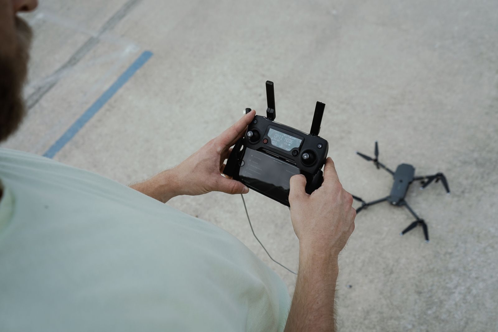 A pilot checks the controller before a small drone takes off