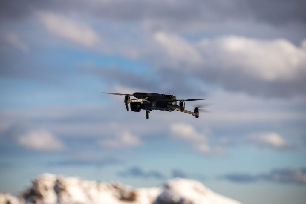 A drone hovering under low clouds over snowy hills