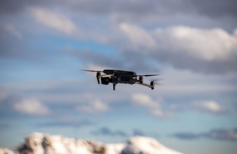 A drone hovering under low clouds over snowy hills