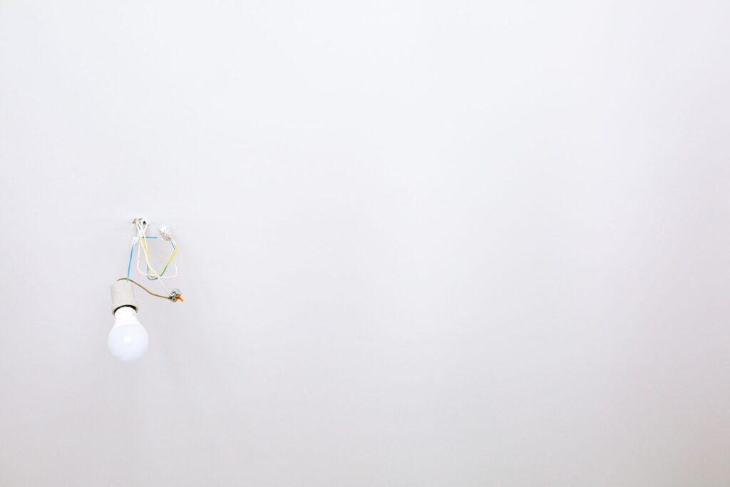 A bare bulb hanging on its wire from a white ceiling