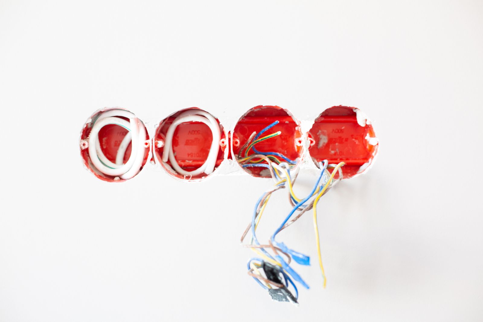 New red outlet boxes set into a white wall with fresh wires ready to connect