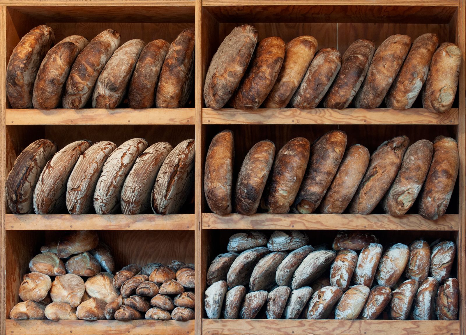 Rows of dark-crusted loaves on wooden bakery shelves