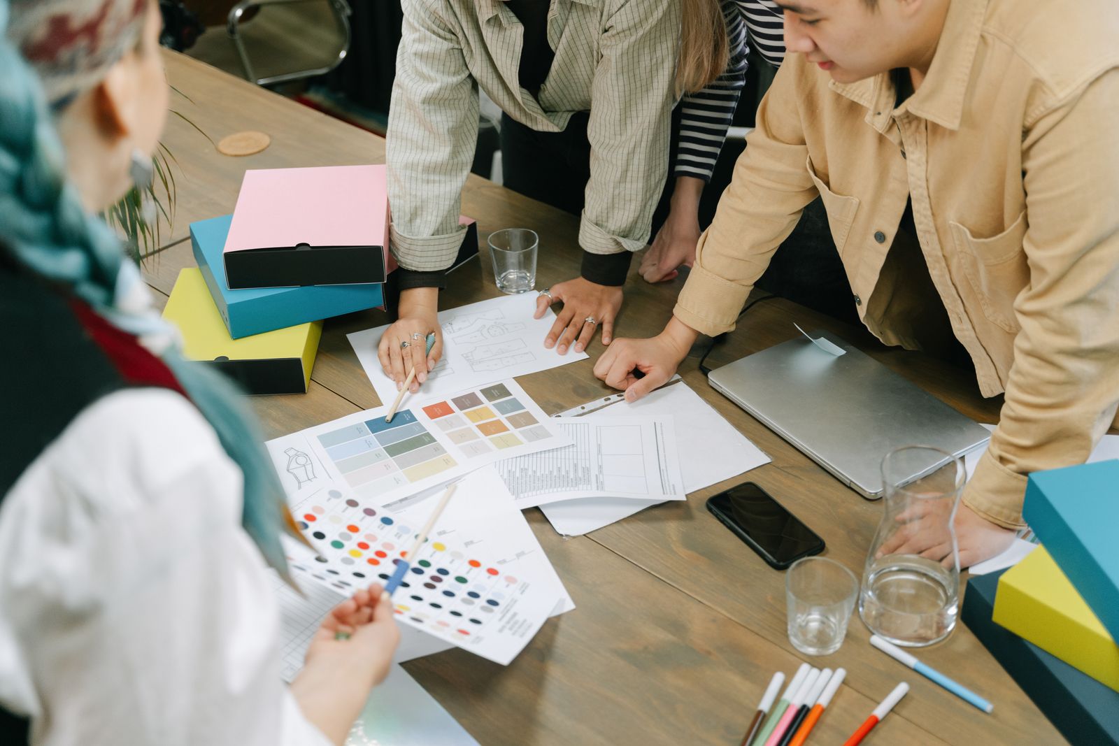 Designers around a table covered with printed colour proofs and swatches