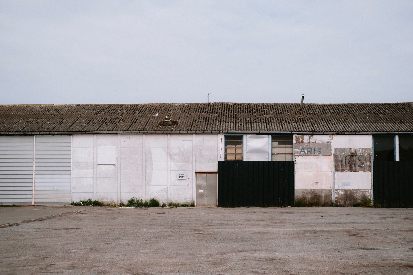 A long, disused depot shed with a weathered front and an empty concrete yard