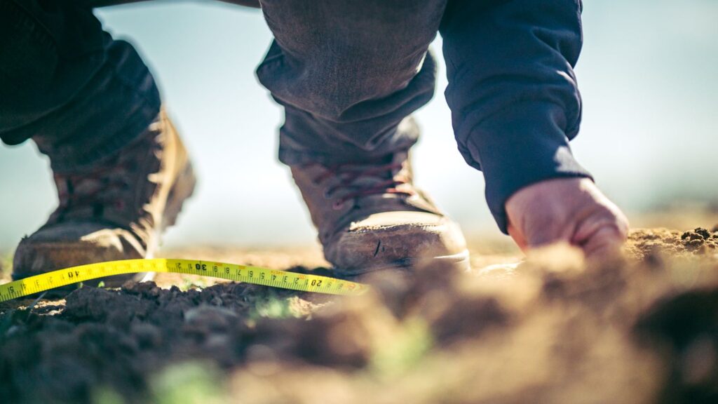 Boots and a measuring tape at the edge of a soil pit