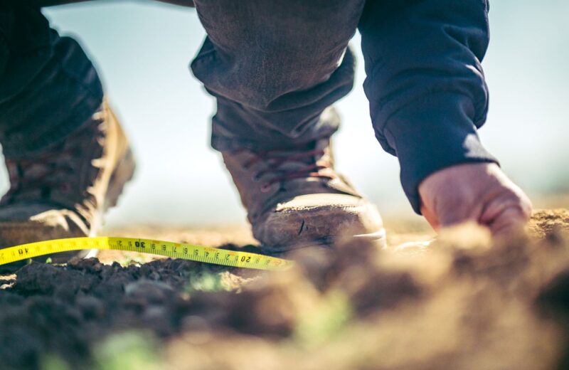 Boots and a measuring tape at the edge of a soil pit
