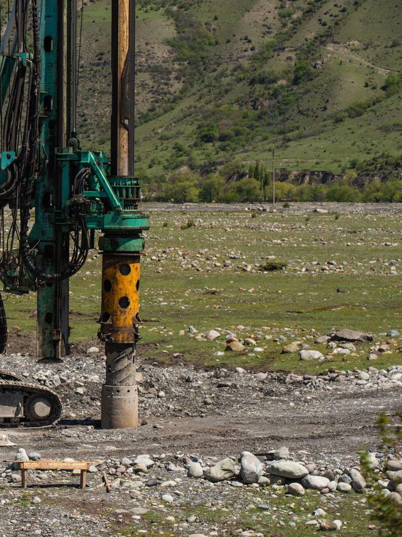 The drilling mast and casing of a rig on rough, stony ground