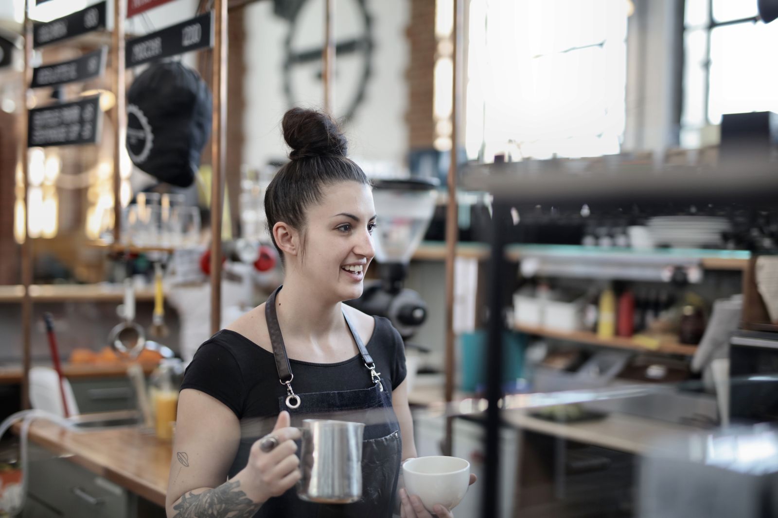 A barista with a milk jug behind a café counter