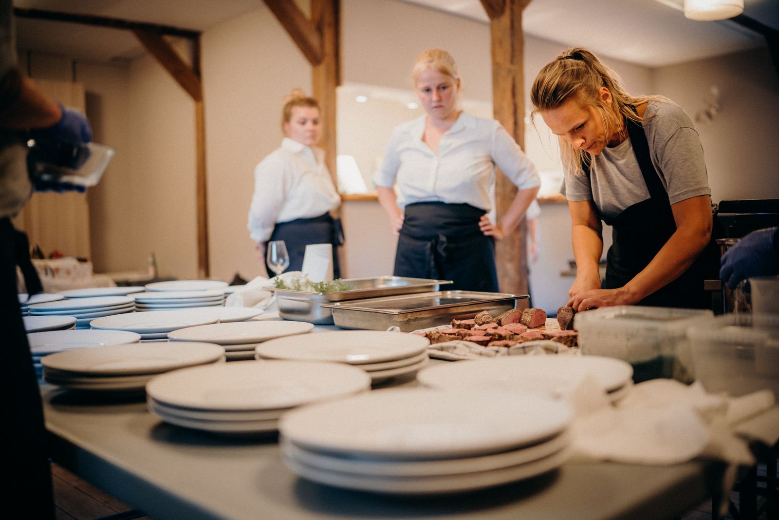 A restaurant kitchen team plating dishes along a steel counter