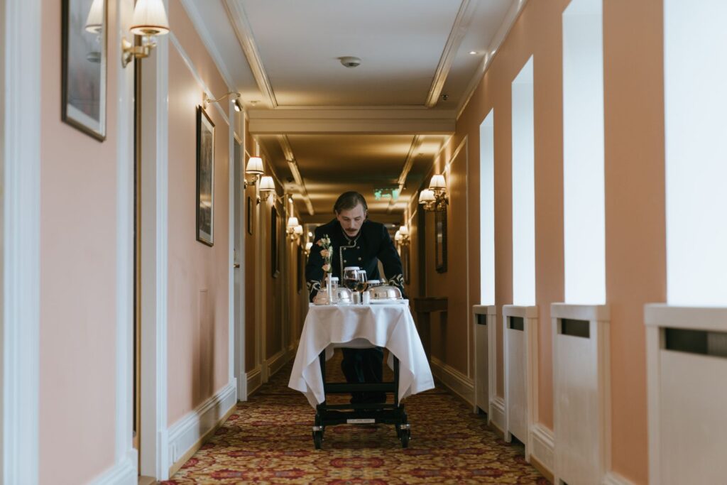 A hotel corridor with a member of staff and a room service trolley
