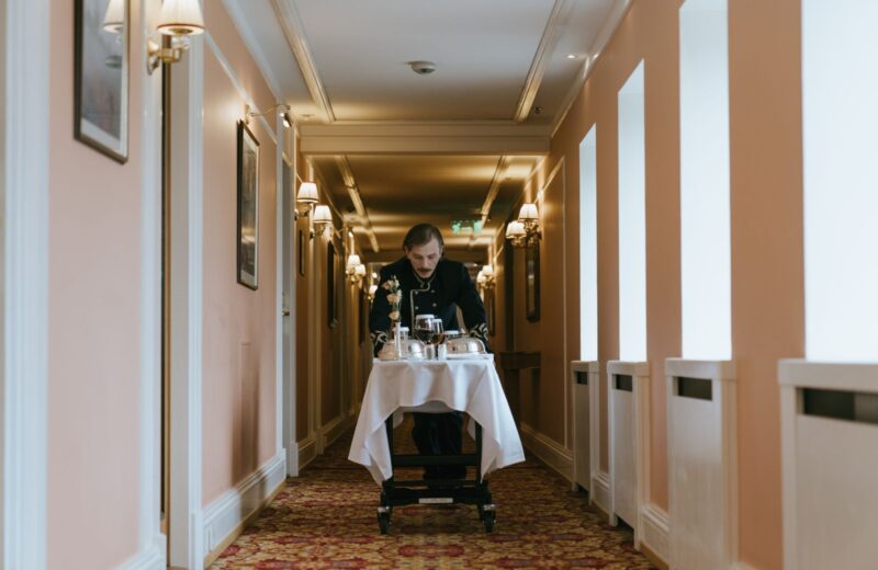 A hotel corridor with a member of staff and a room service trolley