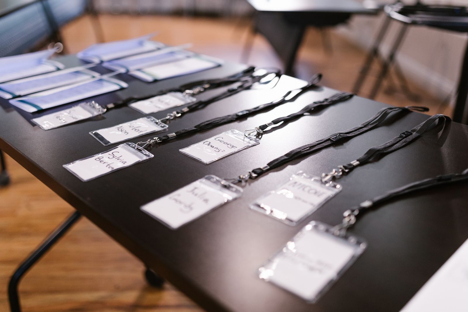 Name badges on black lanyards laid out in rows on a registration table