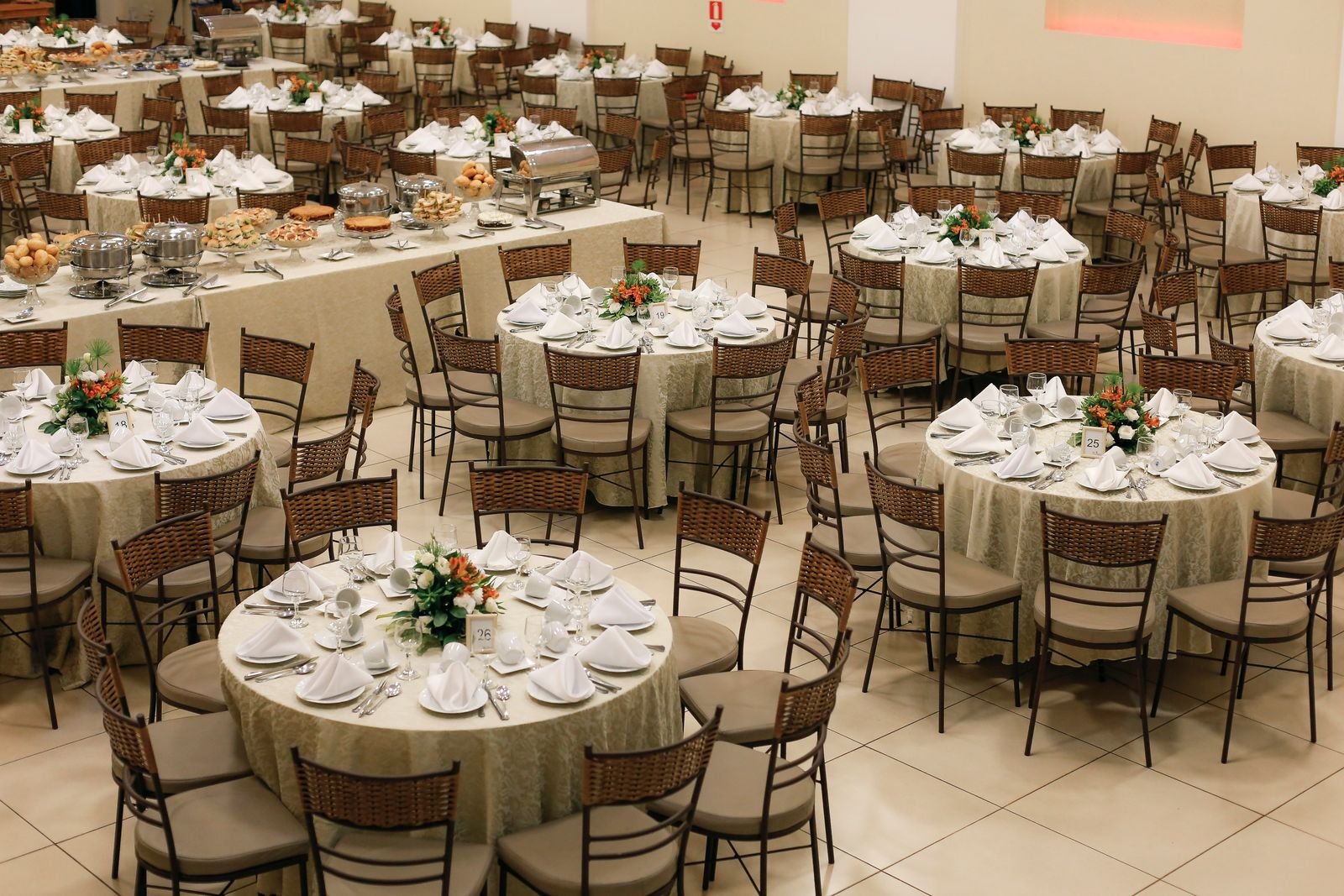 Round tables laid with white cloths and centrepieces in a banquet hall