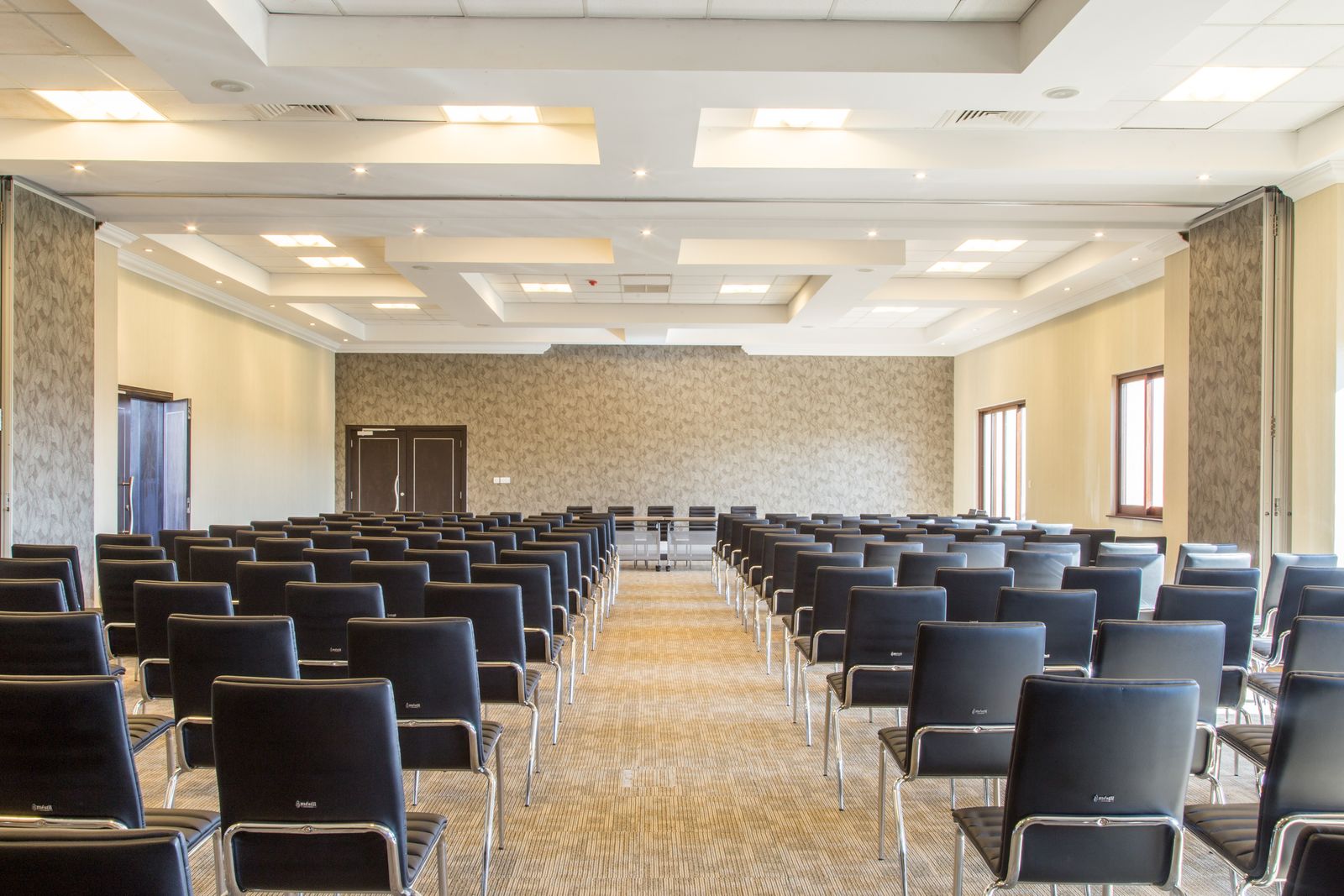 An empty conference room with rows of black chairs facing the front