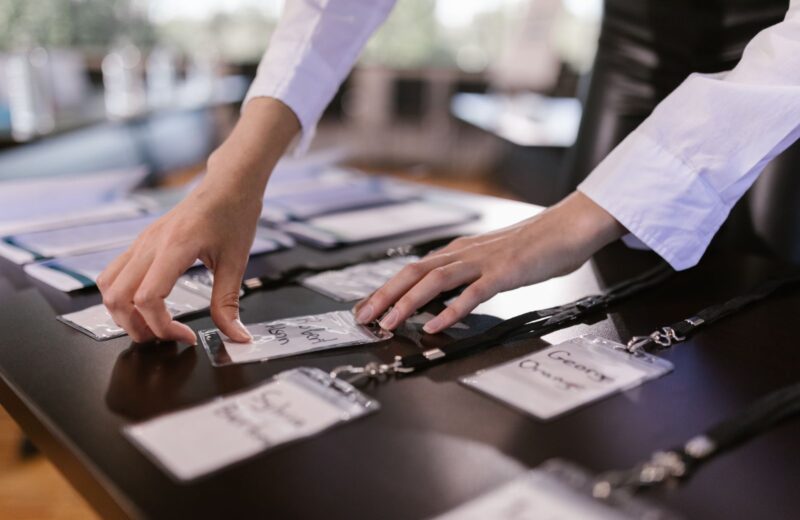Hands arranging name badges and lanyards on a table before an event