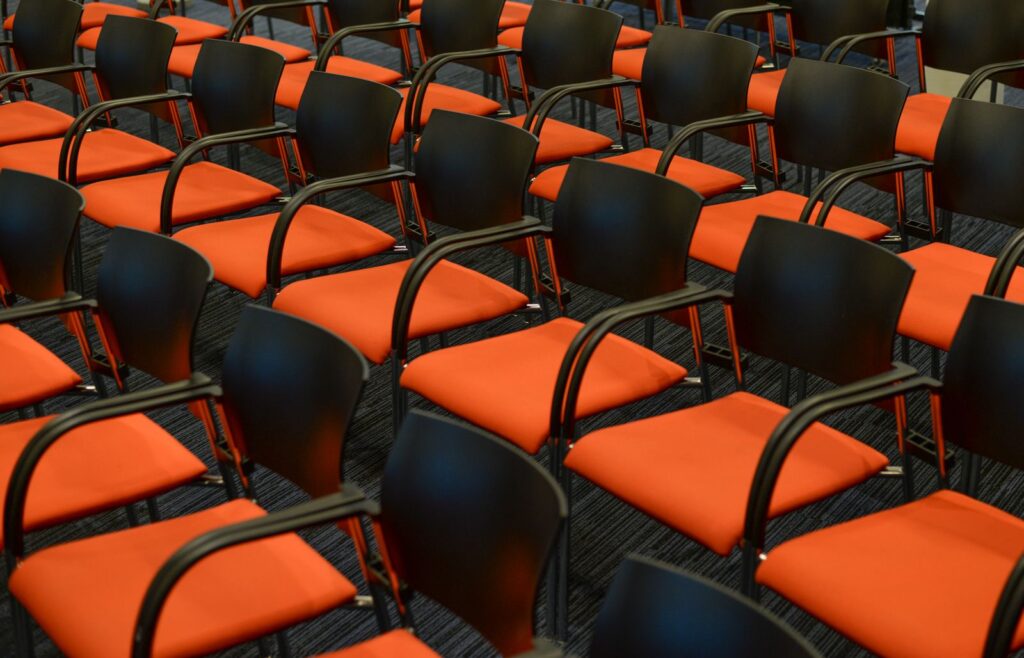 Rows of empty black and orange chairs in an auditorium