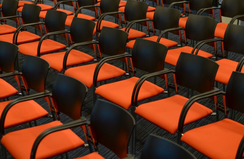 Rows of empty black and orange chairs in an auditorium