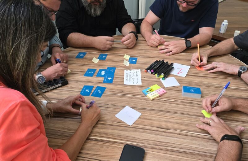 People around a table with cards, markers and sticky notes in a workshop