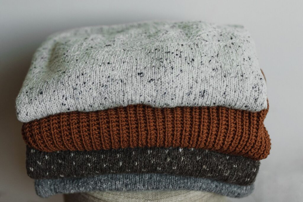 Close-up of folded knit jumpers in oat and cream