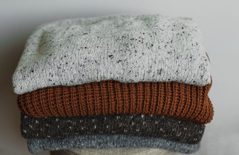 Close-up of folded knit jumpers in oat and cream