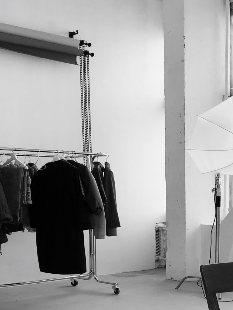 A photo studio with clothing rails, a white backdrop and lights set up for a lookbook shoot
