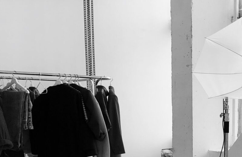 A photo studio with clothing rails, a white backdrop and lights set up for a lookbook shoot