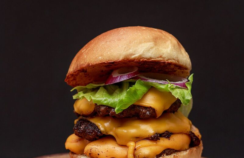A double cheeseburger with lettuce on a wooden board