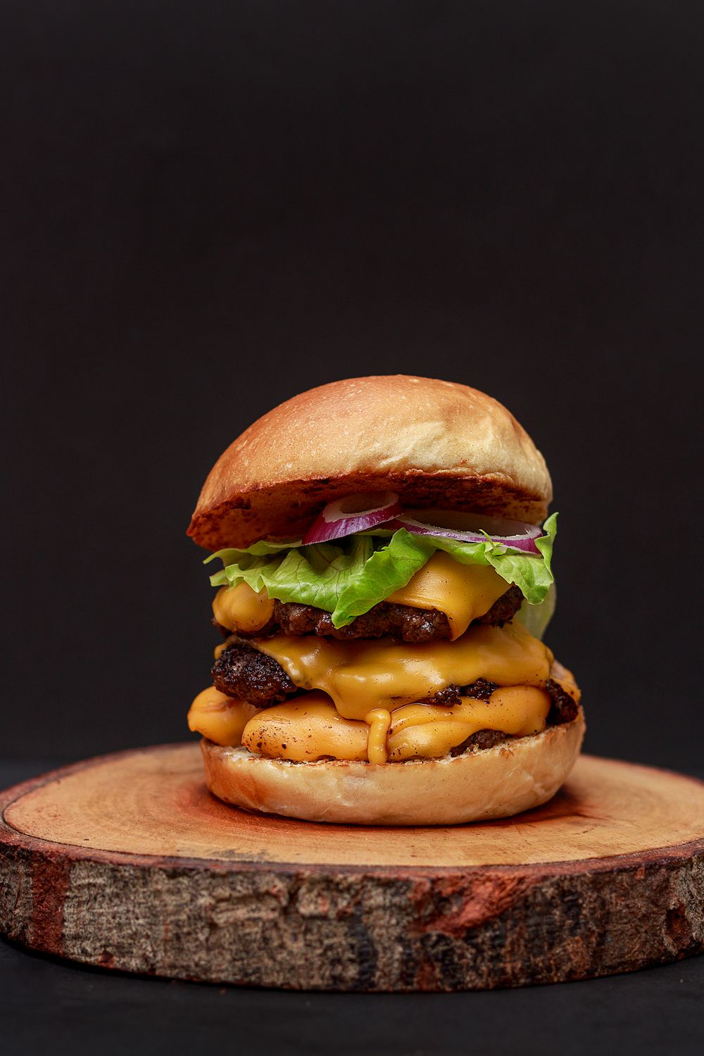 A double cheeseburger with lettuce on a wooden board