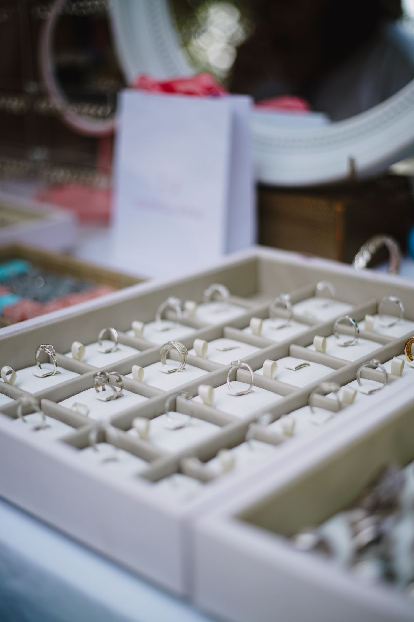 A shop tray of silver rings, each standing in its own slot, under bright window light