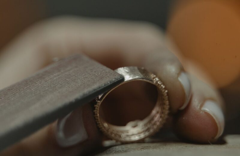 A jeweller polishing a gold ring against a felt wheel, close up