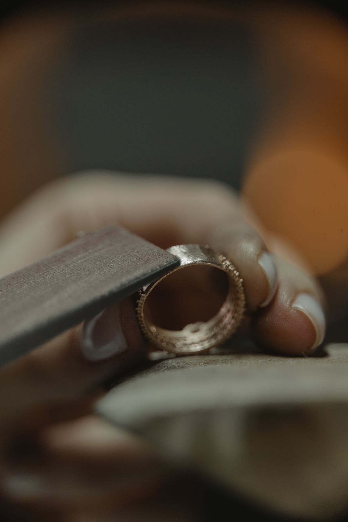 A jeweller polishing a gold ring against a felt wheel, close up