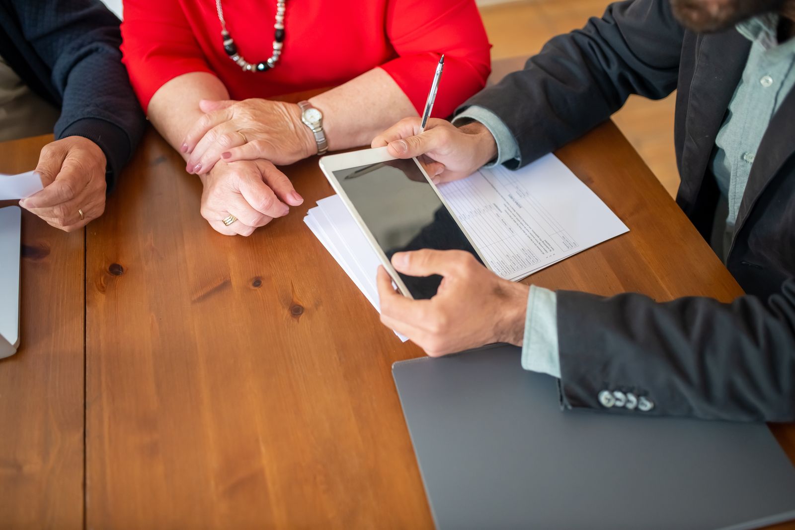 A client and an adviser going through documents and a tablet at a wooden table