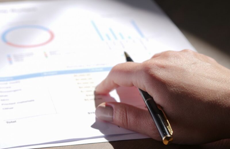 A hand holding a pen over printed charts on paper