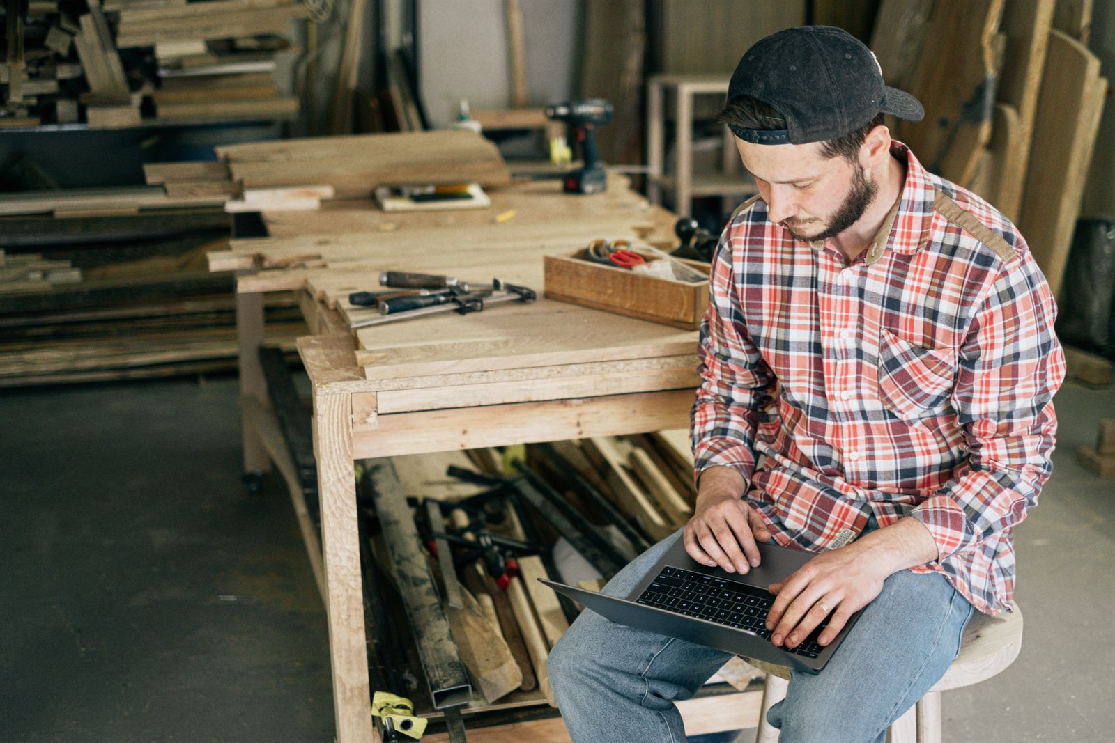 A carpenter doing paperwork on a laptop in his workshop