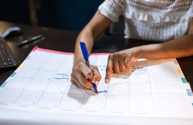 A woman marking dates on a desk calendar