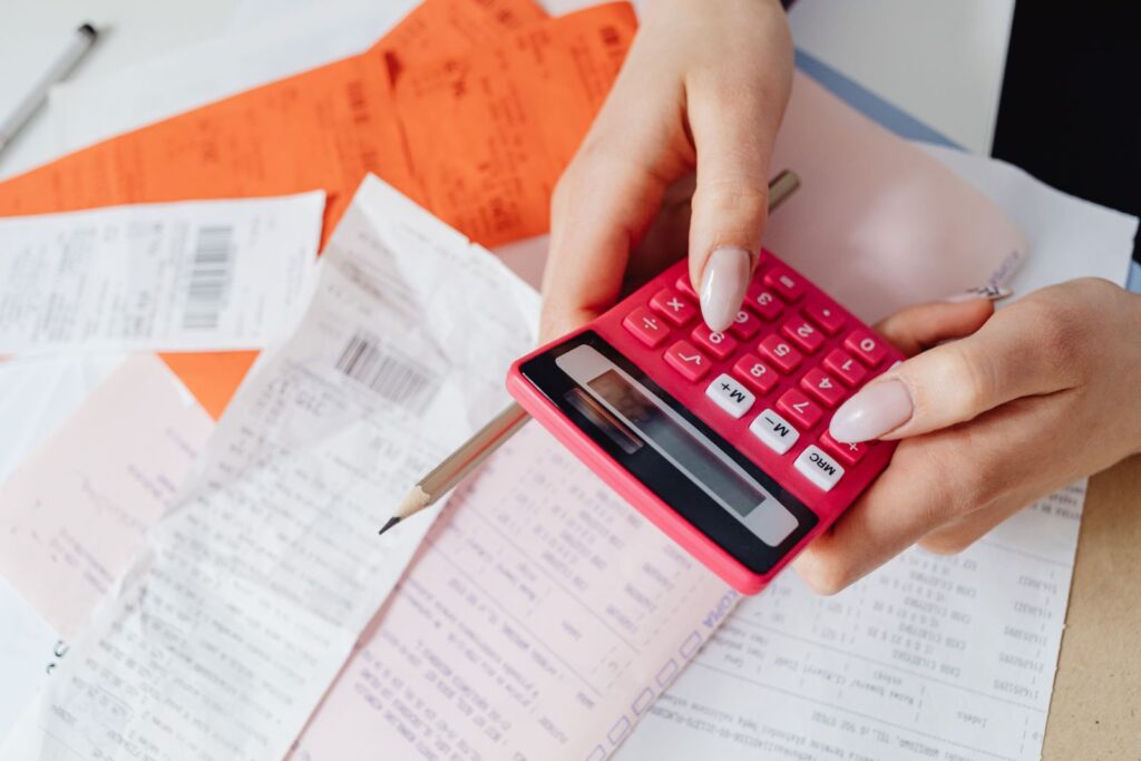 Receipts and bills on a desk beside a calculator