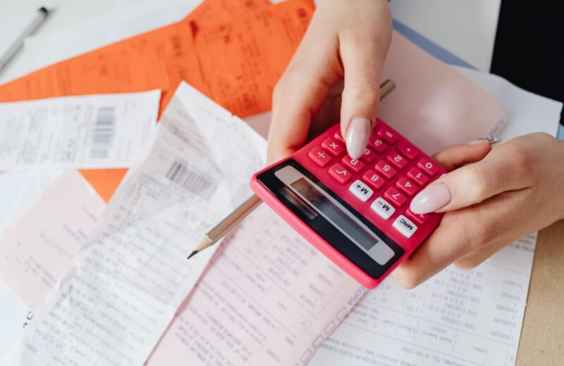 Receipts and bills on a desk beside a calculator