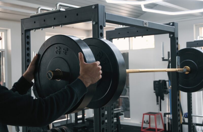 A lifter slides a bumper plate onto a barbell in the rack