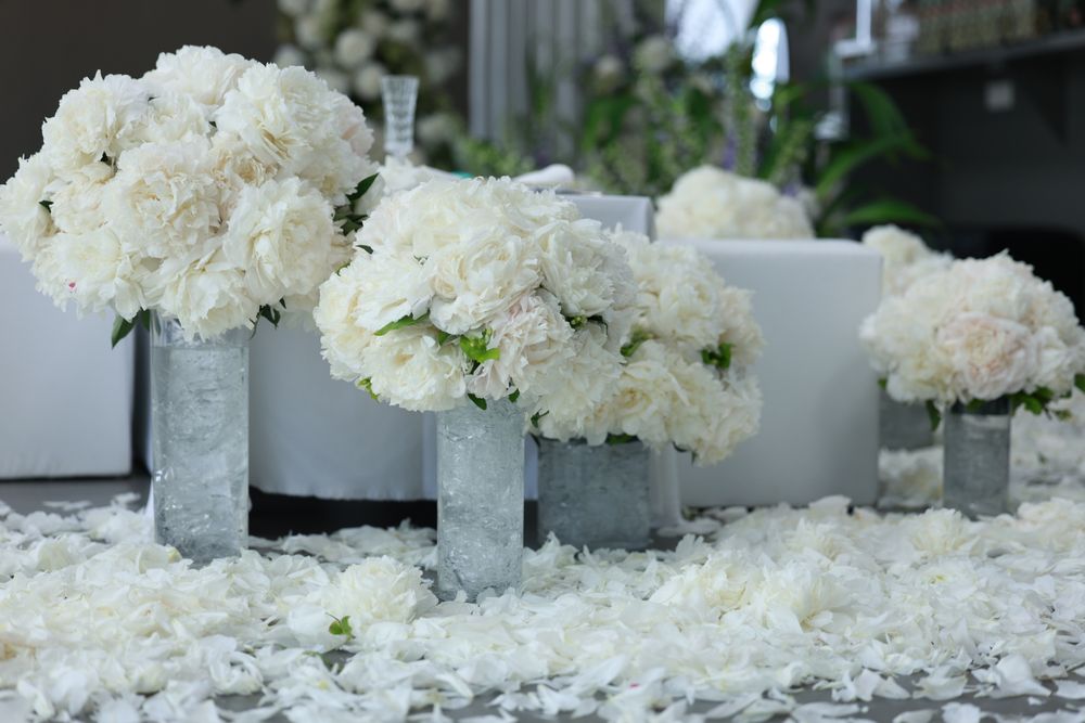 White peony arrangements in silver vases set out for a wedding