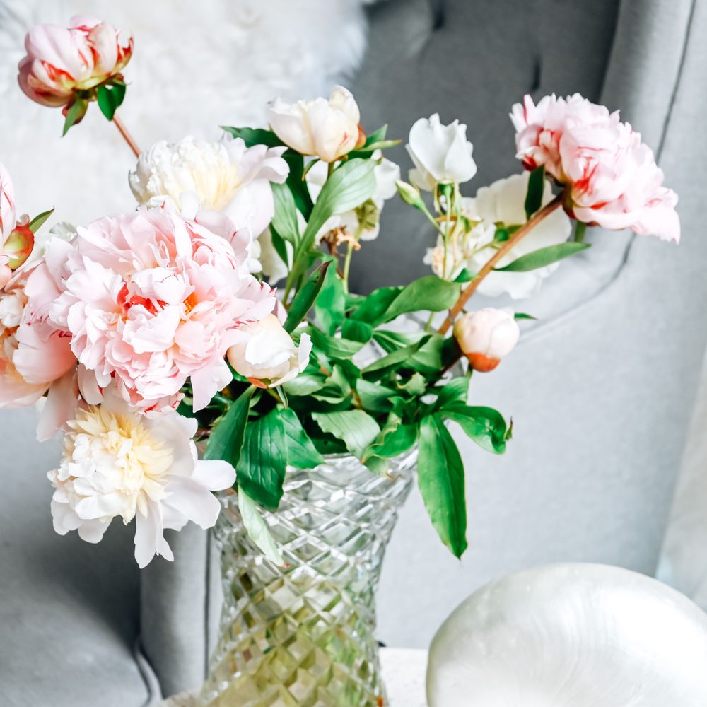 Pink peonies arranged in a glass vase in a calm room