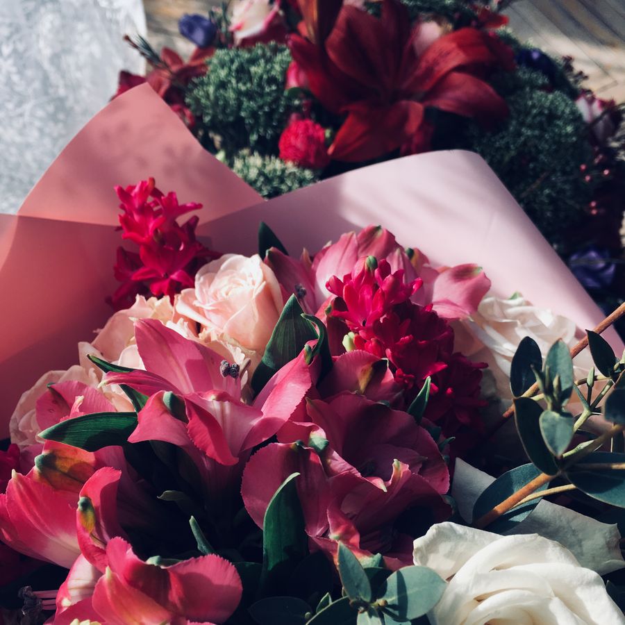 A bunch of roses and lilies in pink craft paper, seen from above