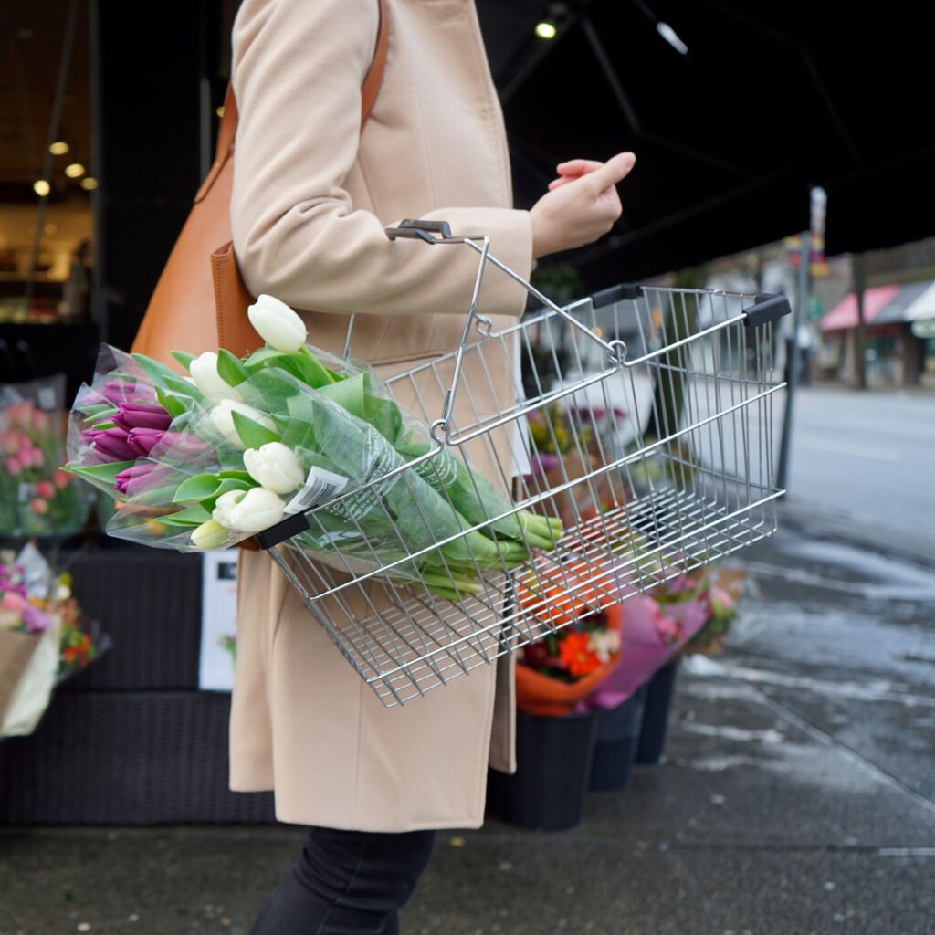 A shopping basket with fresh tulips carried along a street outside a flower shop