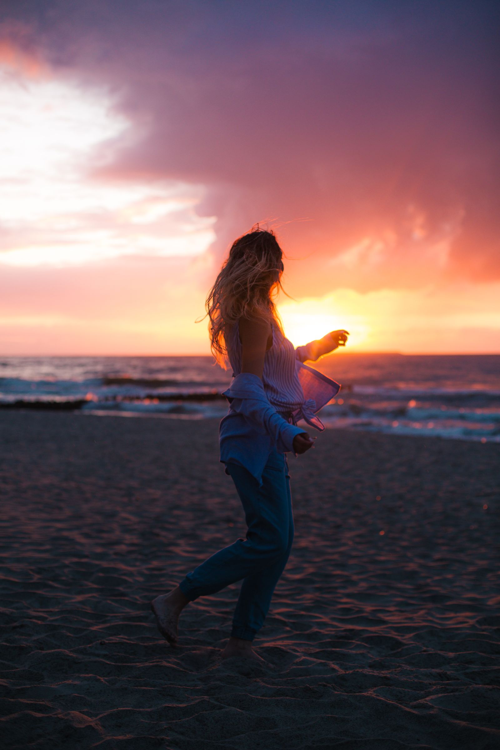 A woman on a beach at sunset, backlit, as the camera recorded it: flat and grey