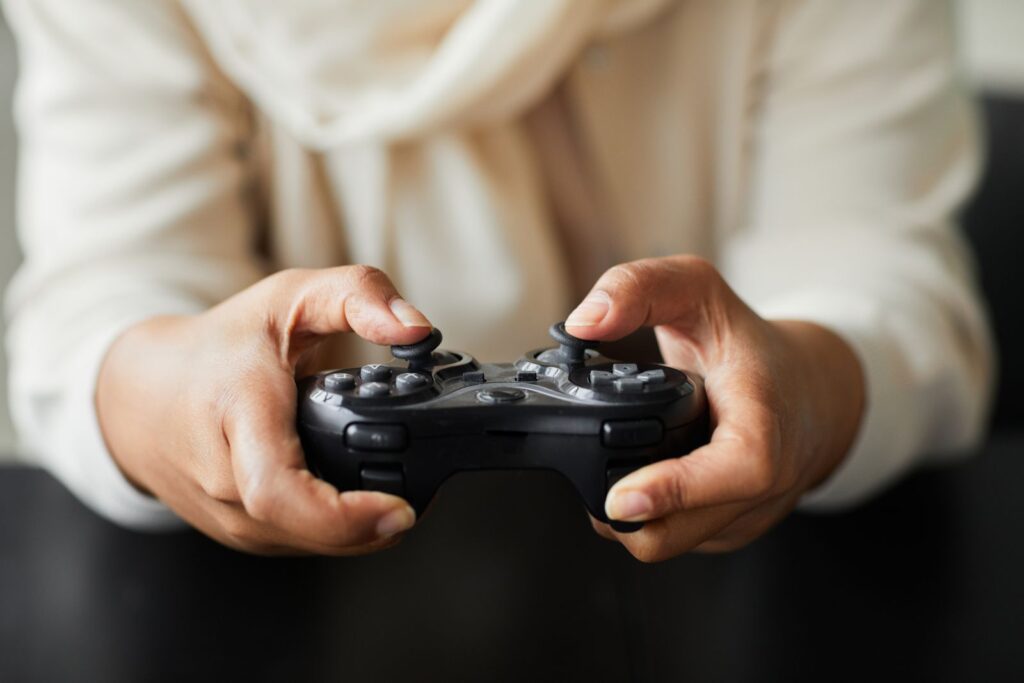 Hands in a cream jumper holding a gamepad