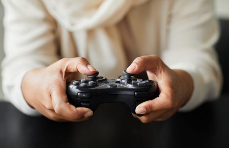 Hands in a cream jumper holding a gamepad