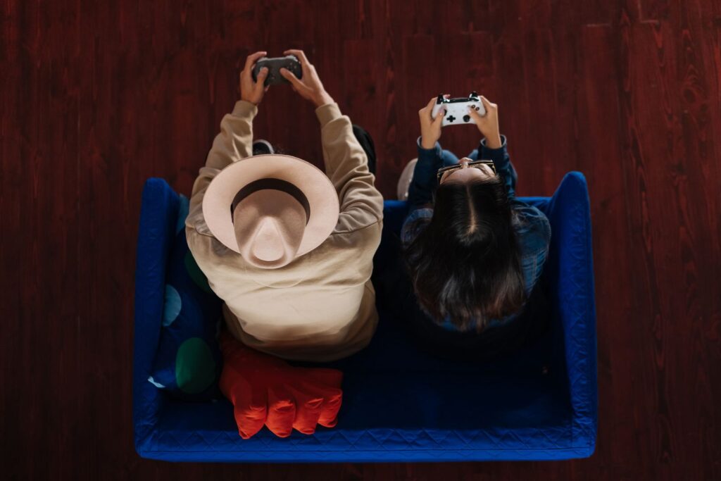 Two friends seen from above, playing on a blue sofa