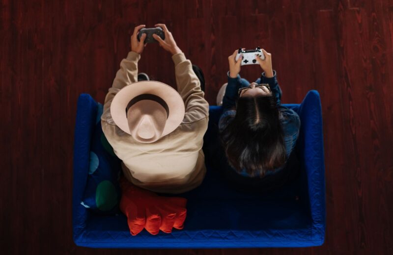 Two friends seen from above, playing on a blue sofa