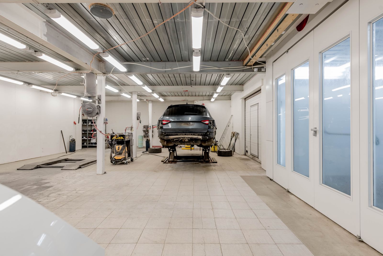 A clean workshop with a car raised on a lift and tools along the wall